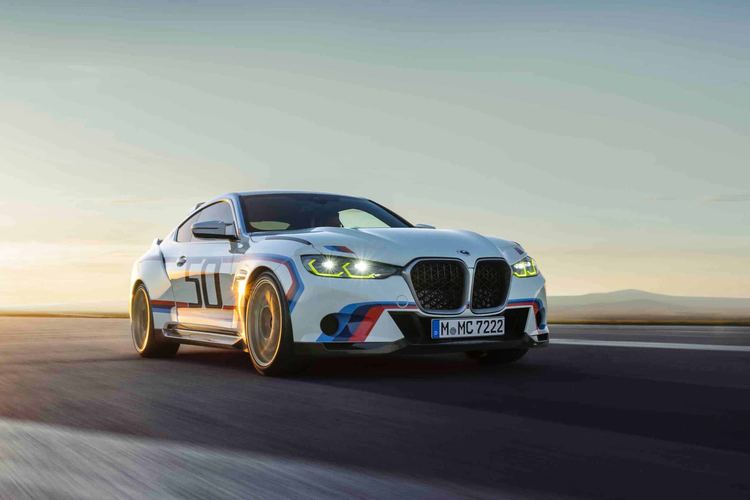 Weißer BMW 3.0 CSL mit M-Streifen in Blau, Violett und Rot und großer Startnummer 50 fährt in der Abendsonne