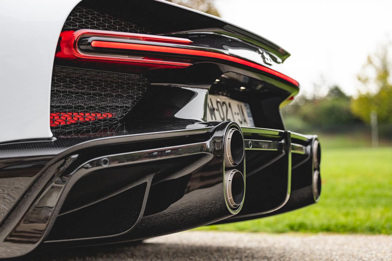 Nahaufnahme des Hecks eines weißen Bugatti Chiron Super Sport mit Leuchtband, Wabengitter und vier Endrohren